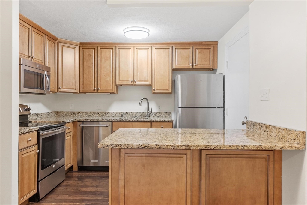 420 Great Road, Unit C1 Acton, MA 01720 - Photo 22 of 29 a kitchen with stainless steel appliances granite countertop a stove a sink dishwasher a refrigerator and cabinets with wooden floor