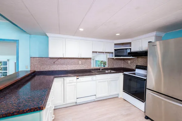 a kitchen with granite countertop white cabinets and wooden floor