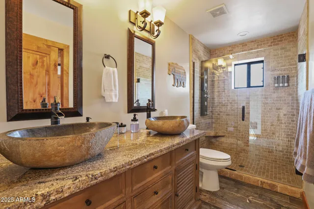 a bathroom with a granite countertop sink a toilet a mirror and shower