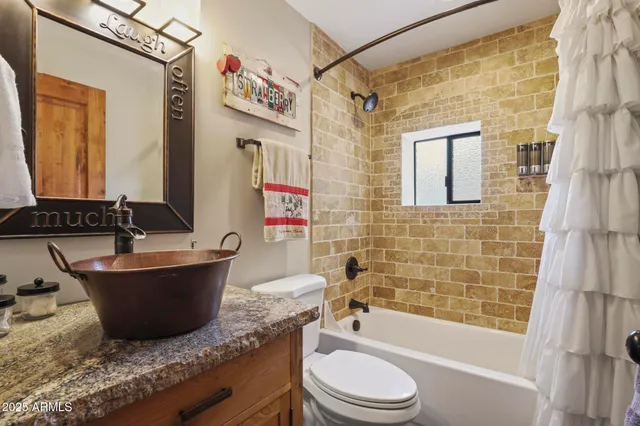 a bathroom with a granite countertop bathtub sink mirror vanity and toilet