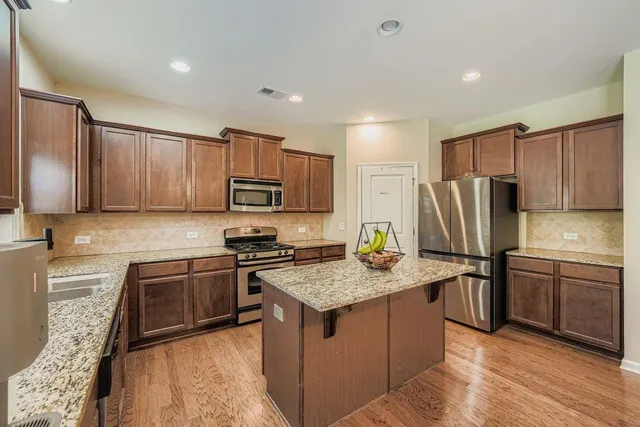 a kitchen with stainless steel appliances granite countertop a refrigerator stove microwave and sink