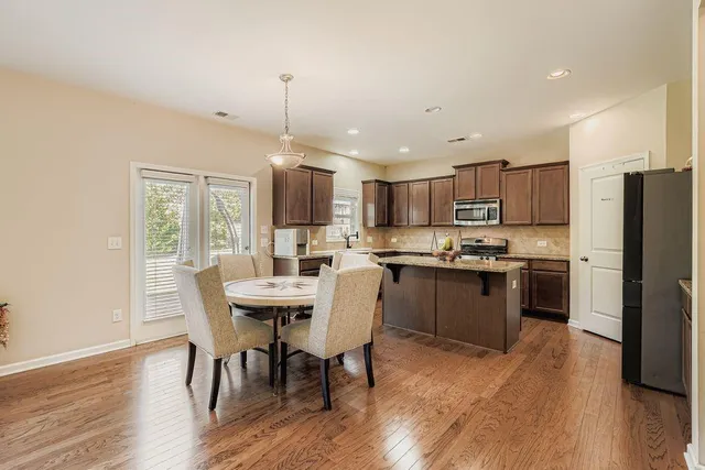 a kitchen with a refrigerator a dining table and chairs