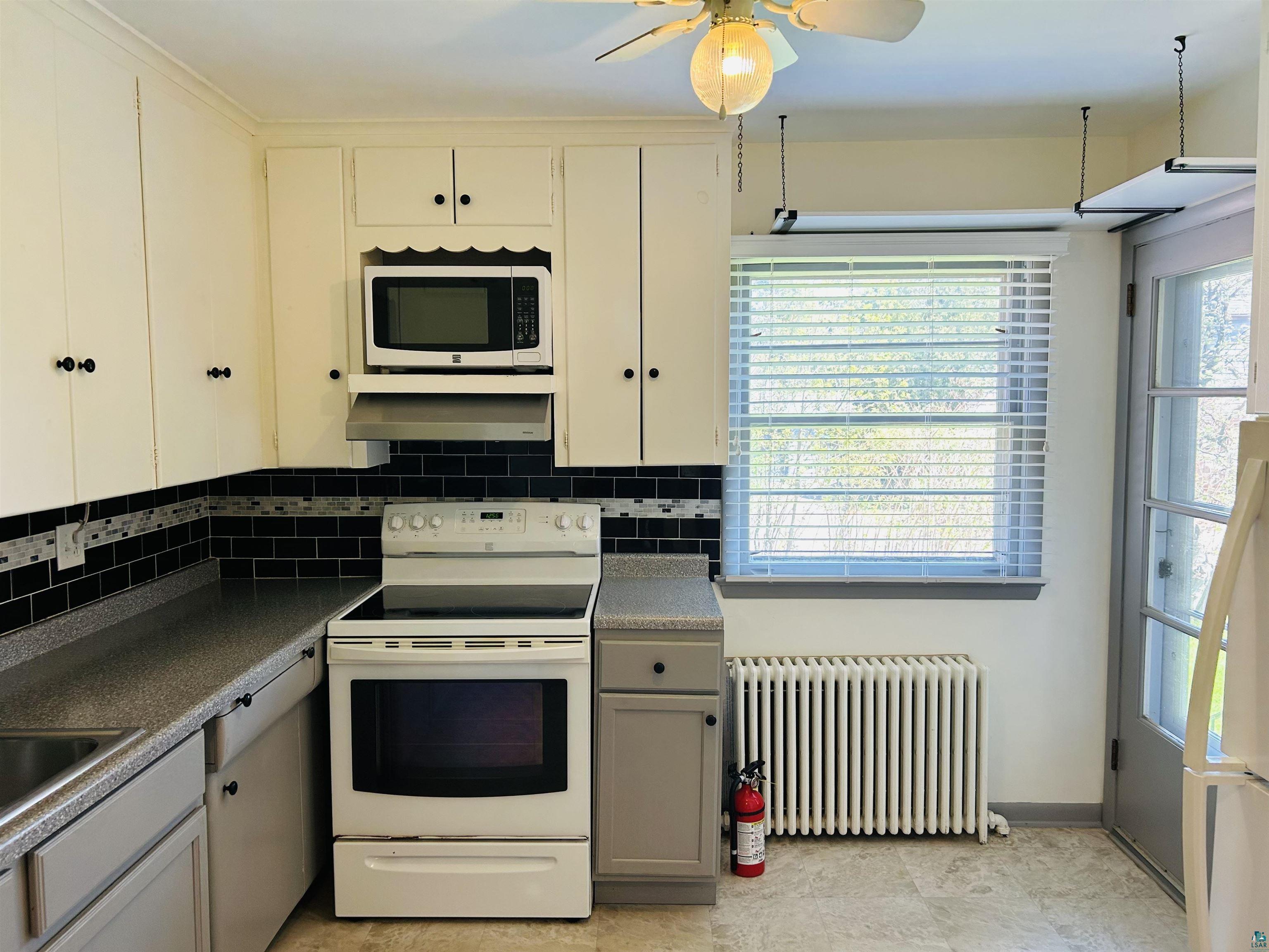 5090 London Road, Unit 1 Duluth, MN 55804 - Photo 10 of 54 Kitchen featuring white cabinetry with black hardware, black subway tile backsplash, and speckled countertops