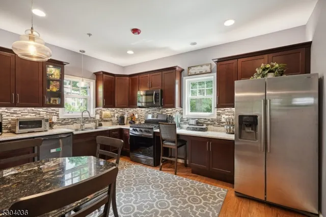 a kitchen with stainless steel appliances granite countertop sink stove refrigerator dining table and chairs