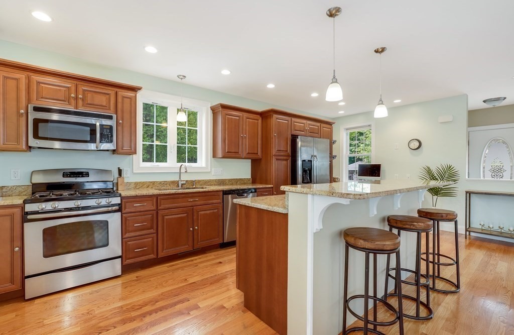 10 Maple Way Wakefield, MA 01880 - Photo 9 of 26 a kitchen with stainless steel appliances granite countertop a stove top oven a sink dishwasher a dining table and chairs with wooden floor