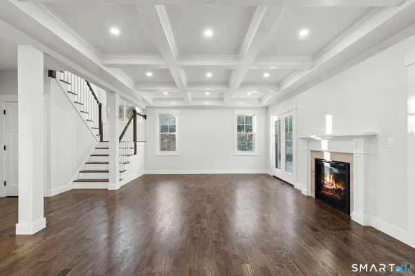 an empty room with wooden floor fireplace and windows