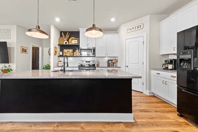 a kitchen with stainless steel appliances granite countertop a refrigerator a sink a stove and a wooden floors