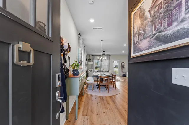 a view of a hallway to room with wooden floor and closet