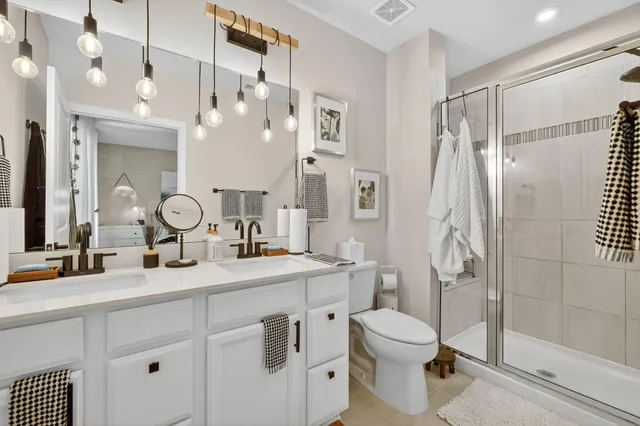a bathroom with a double vanity sink toilet mirror and shower