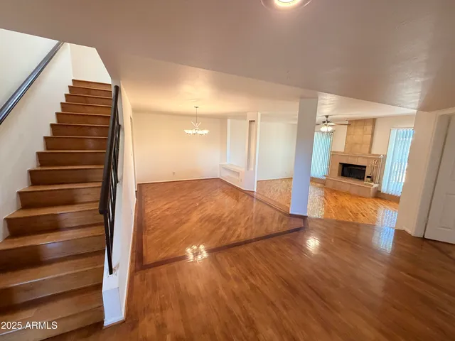 a view of an empty room with wooden floor and stairs