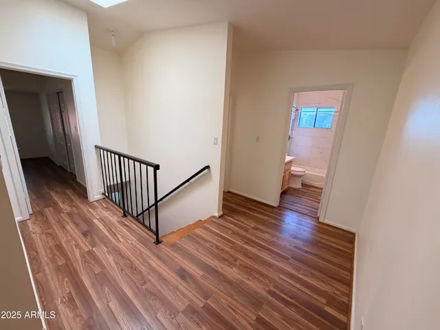 a view of a hallway with wooden floor and a bathroom