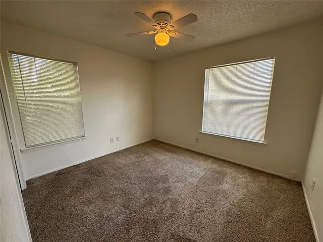an empty room with windows and fan