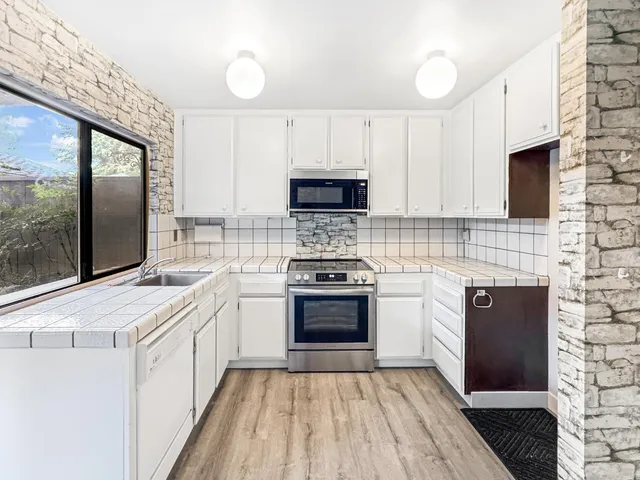 a kitchen with stainless steel appliances a stove a sink and a microwave
