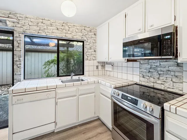 a kitchen with cabinets appliances a sink and a window