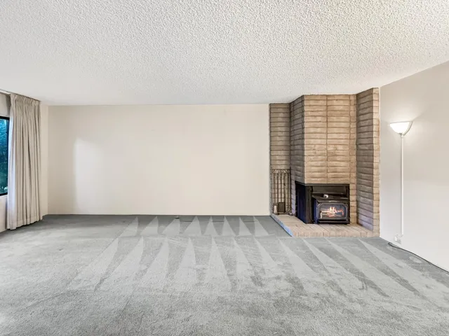 a view of an empty room with a fireplace and a window