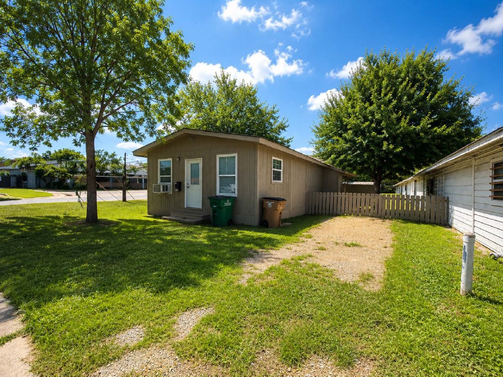 610 Gunter Street Austin, TX 78702 - Photo 2 of 16 A modest single-story home with a well-maintained lawn and surrounding mature trees.