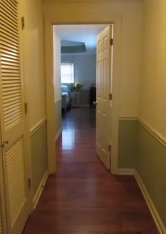 a view of a hallway with wooden floor and a bathroom