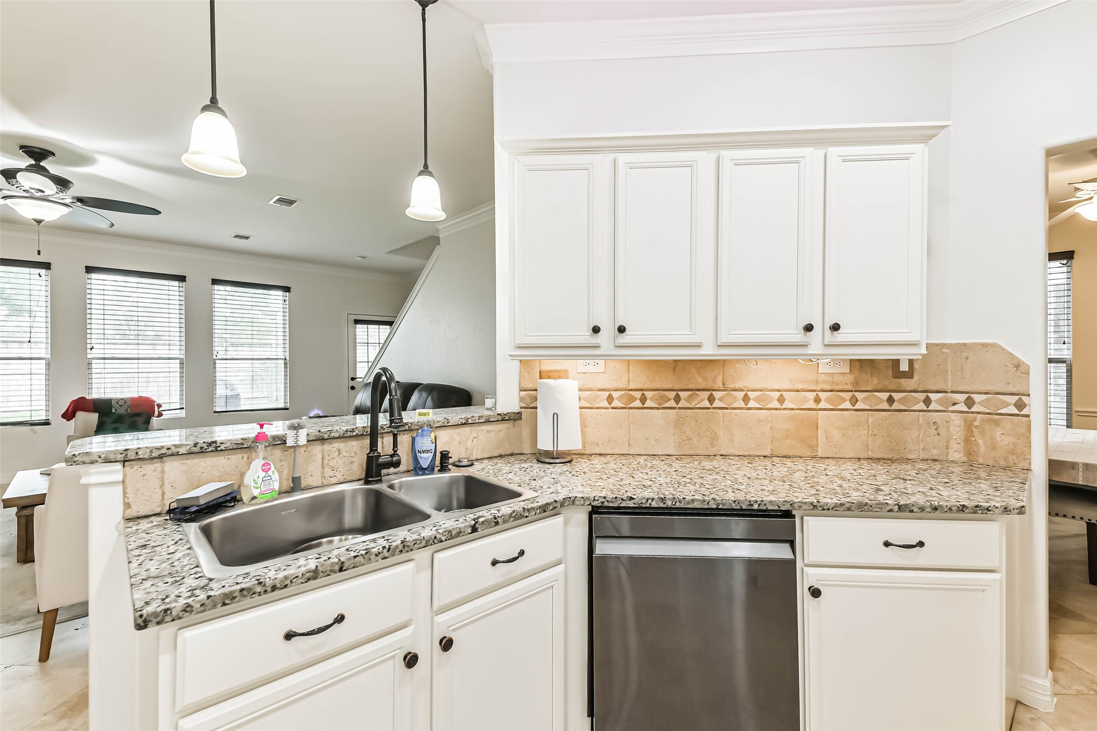 22538 Goss Spring Court Spring, TX 77373 - Photo 11 of 36 This photo showcases a bright, open-concept kitchen with granite countertops, white cabinets, and stainless steel appliances. The space connects to the living area, which features large windows, creating a welcoming and airy atmosphere.