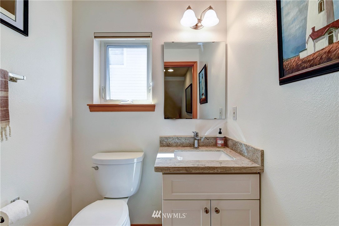 1311 North 145th Street, Unit B Seattle, WA 98133 - Photo 13 of 31 a bathroom with a granite countertop toilet a sink and a mirror