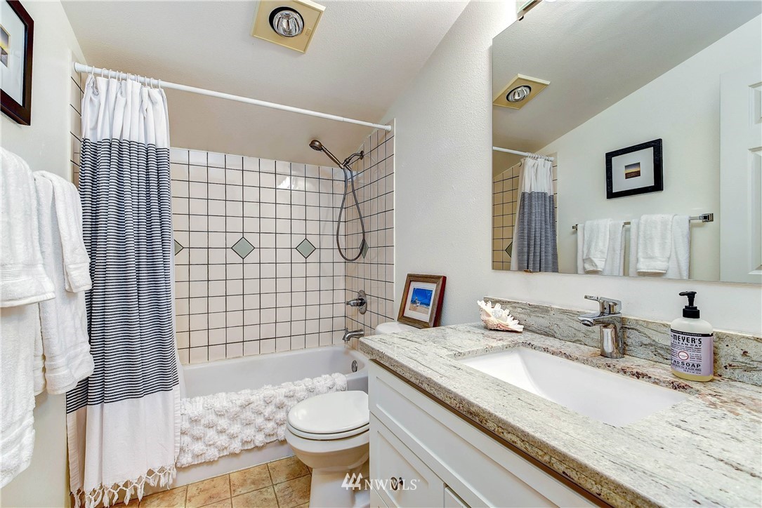 1311 North 145th Street, Unit B Seattle, WA 98133 - Photo 16 of 31 a bathroom with a granite countertop toilet sink and mirror