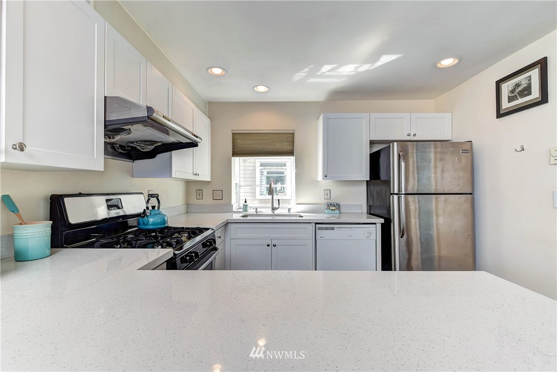 1311 North 145th Street, Unit B Seattle, WA 98133 - Photo 3 of 31 a kitchen with granite countertop a refrigerator stove top oven and sink