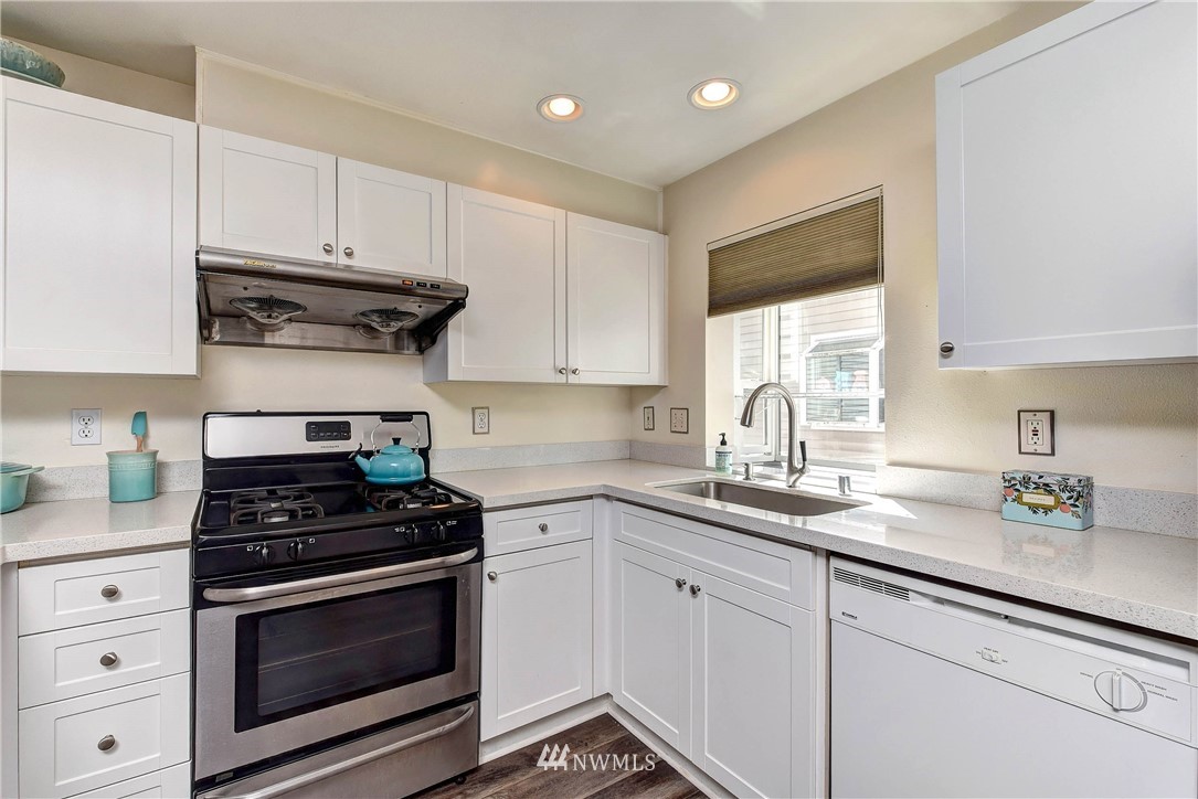 1311 North 145th Street, Unit B Seattle, WA 98133 - Photo 4 of 31 a kitchen with granite countertop white cabinets and stainless steel appliances