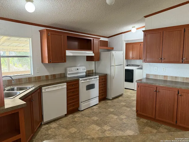 a kitchen with stainless steel appliances granite countertop a stove top oven a sink dishwasher and a refrigerator with wooden cabinets