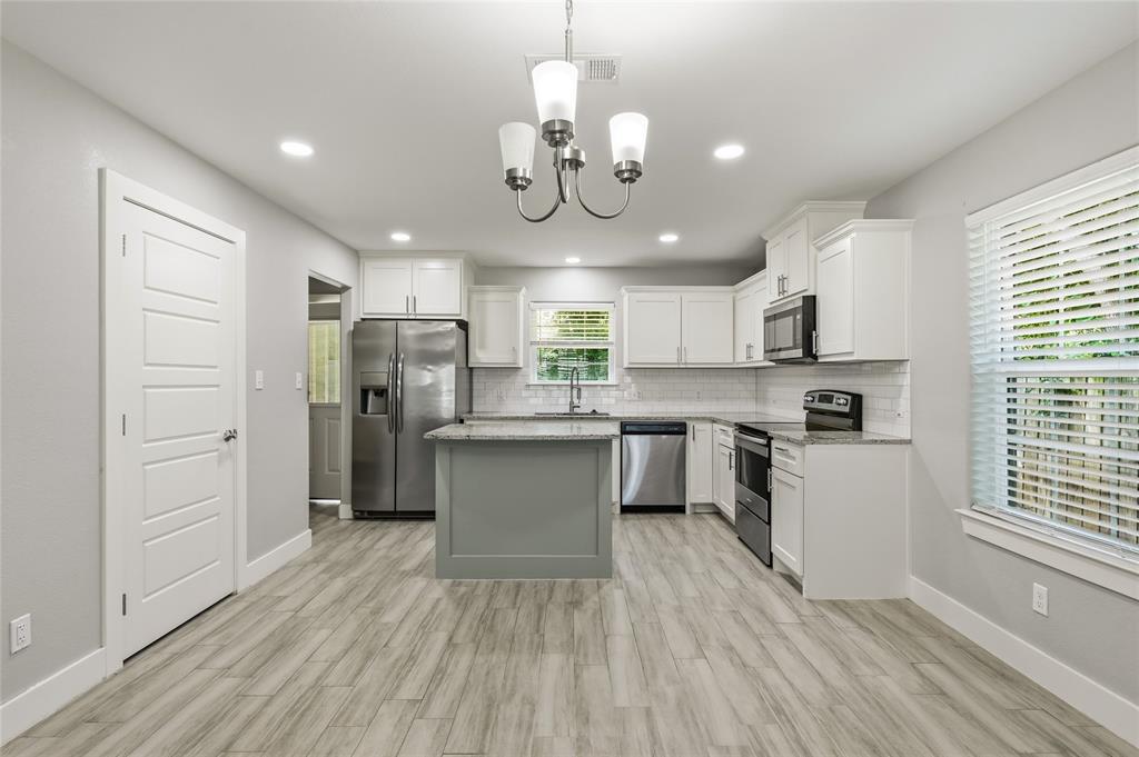 318 Munson Street Denison, TX 75021 - Photo 5 of 21 a kitchen with stainless steel appliances granite countertop a refrigerator a stove top oven a sink dishwasher and white cabinets with wooden floor