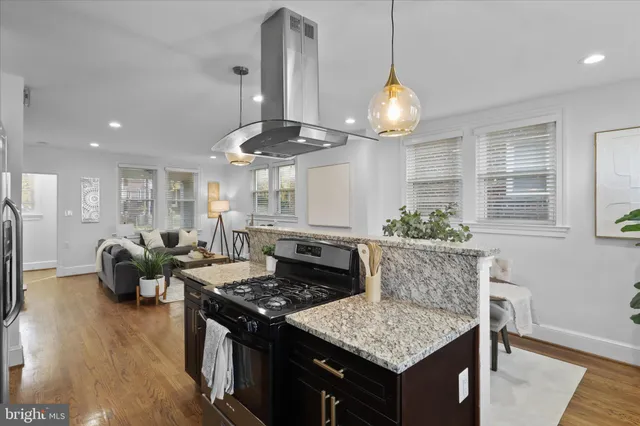 a kitchen with stainless steel appliances granite countertop a stove a chimney a refrigerator and a wooden floors