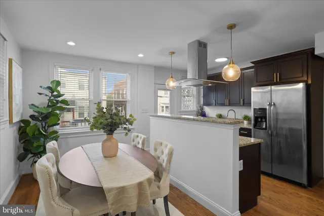 a kitchen with stainless steel appliances a dining table chairs and refrigerator