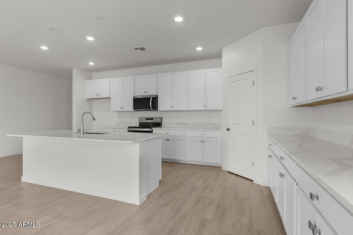 18168 West Pima Street Goodyear, AZ 85338 - Photo 4 of 21 a kitchen with white cabinets and white appliances