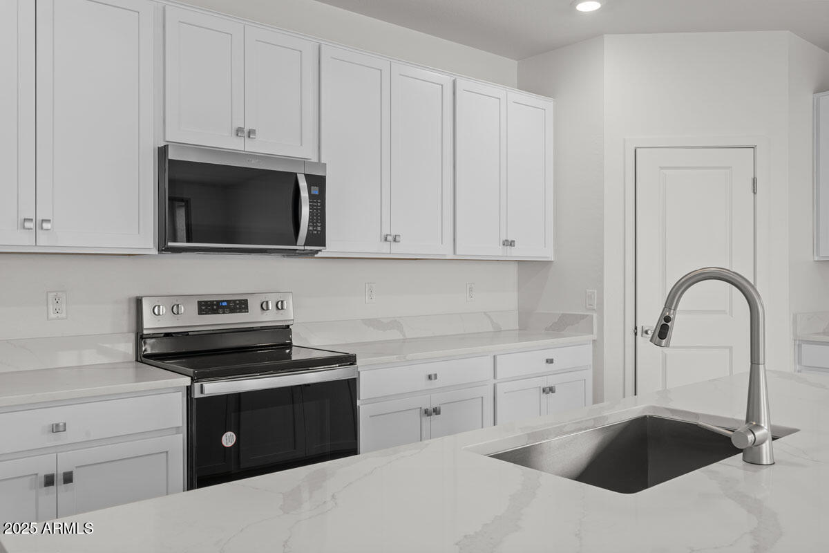18168 West Pima Street Goodyear, AZ 85338 - Photo 6 of 21 a kitchen with granite countertop white cabinets and stainless steel appliances