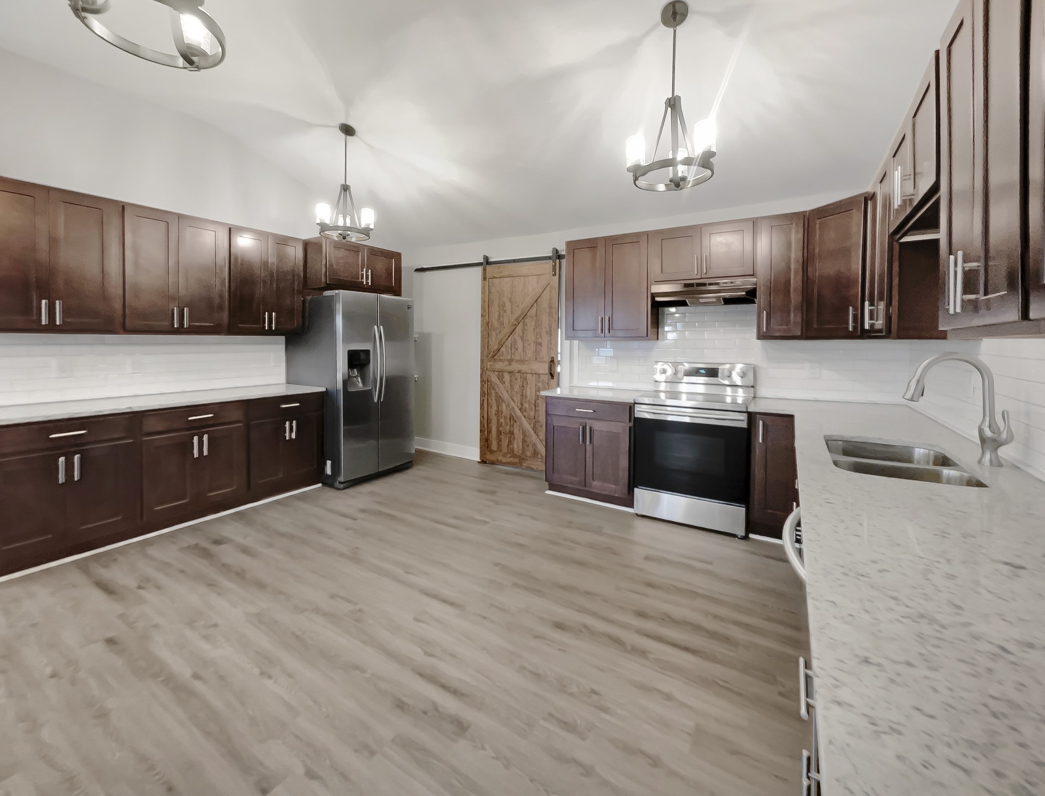 310 Tom Link Road Cottontown, TN 37048 - Photo 7 of 44 a large kitchen with stainless steel appliances wooden cabinets a sink dishwasher a stove and a refrigerator with wooden floor