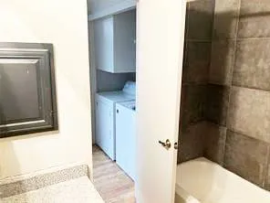 a view of an empty room with wooden floor and fan