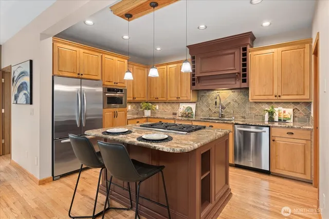 a kitchen with stainless steel appliances granite countertop a sink a stove a refrigerator cabinets and chairs