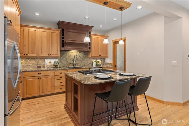 a kitchen with stainless steel appliances granite countertop a stove a sink dishwasher and a refrigerator with wooden cabinets