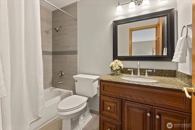 a bathroom with a granite countertop toilet sink and mirror
