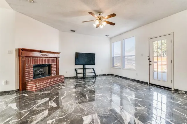 a view of livingroom with a fireplace a ceiling fan and windows