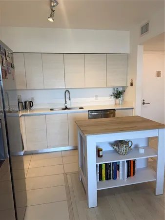 a utility room with stainless steel appliances a stove a sink and a refrigerator