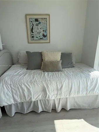 a large white bed sitting in a bedroom and painting on the wall