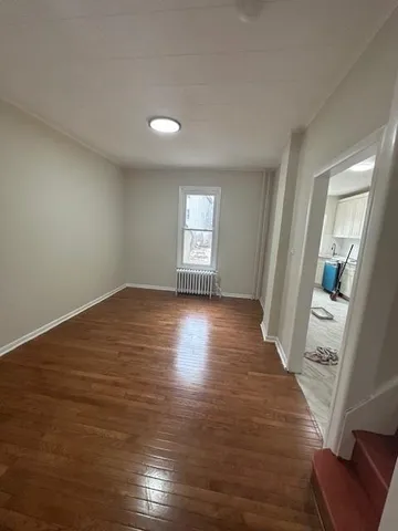 a view of empty room with window and wooden floor