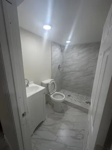 a bathroom with a granite countertop sink toilet and shower