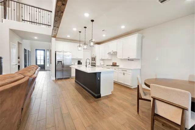 a large kitchen with stainless steel appliances a large counter top a sink a stove and a refrigerator