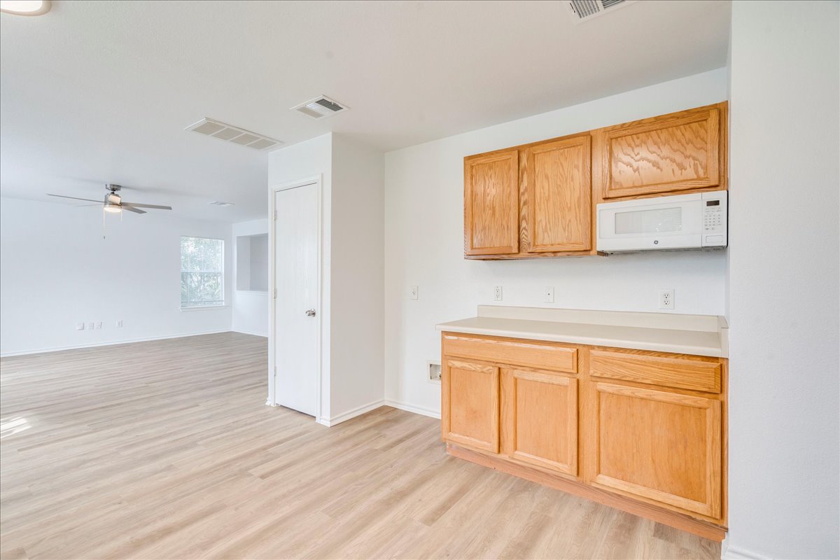 618 Lavaca Loop Elgin, TX 78621 - Photo 30 of 30 Kitchen featuring light countertops, white microwave, light wood-style flooring, ceiling fan, and open floor plan