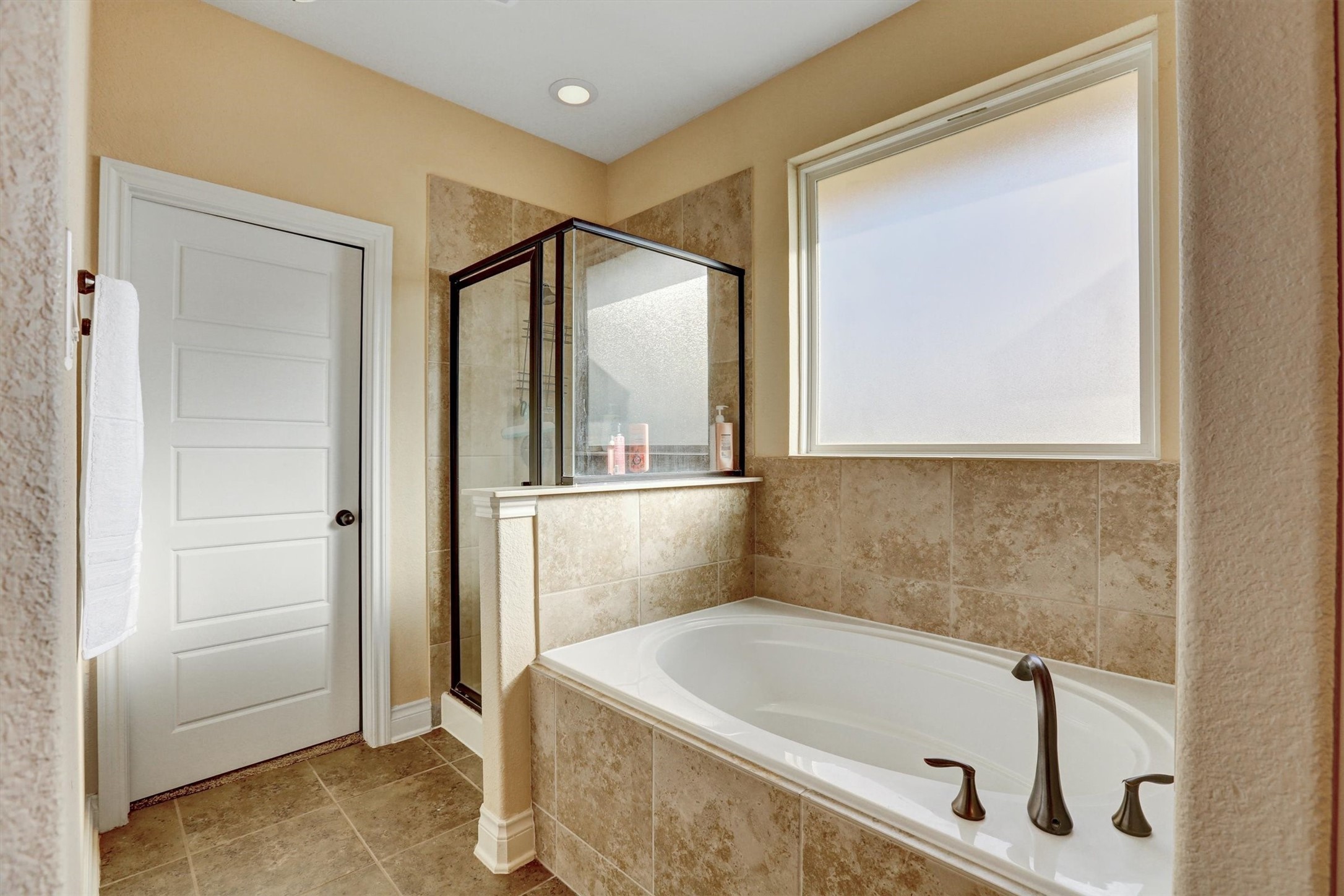 8131 Brinkmeyer Road Needville, TX 77461 - Photo 38 of 49 Experience relaxation in this elegant bathroom featuring a spacious soaking tub, a separate glass-enclosed shower, and warm tile accents throughout.