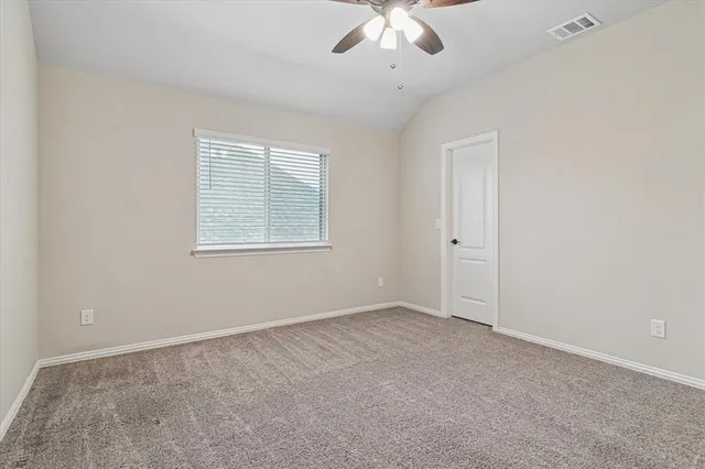 an empty room with a chandelier fan and windows