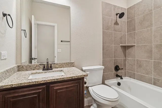 a bathroom with a granite countertop sink a toilet and shower