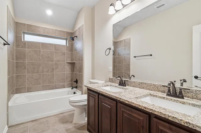 a bathroom with a granite countertop bathtub sink double vanity and toilet