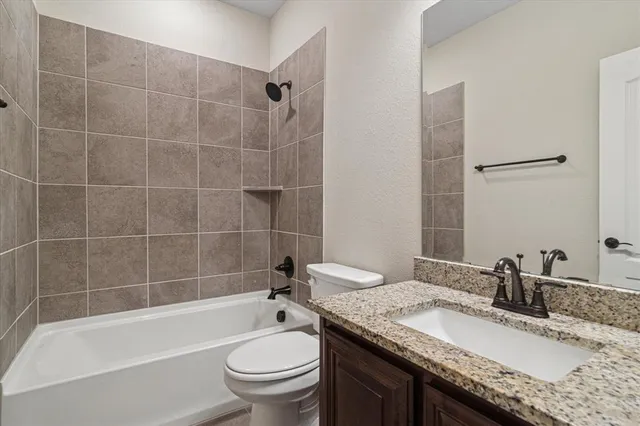 a bathroom with a granite countertop sink a toilet and bathtub