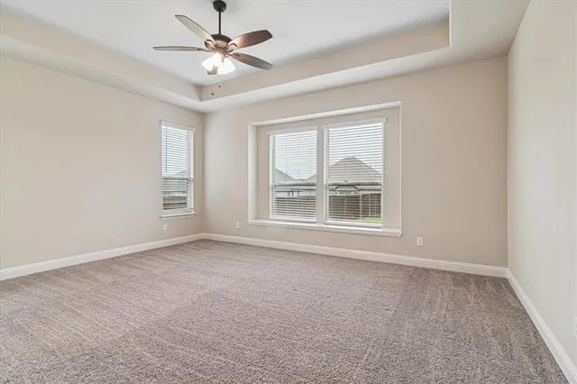 an empty room with chandelier fan and windows